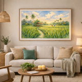 A framed landscape painting of a lush green rice field with palm trees and a small hut under a bright sky, displayed on a beige wall above a light-colored sofa in a styled living room.