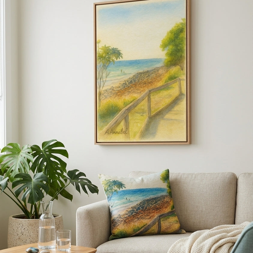 A framed coastal landscape painting hangs on a light wall above a beige sofa with a matching printed pillow, in a styled living room with a side table, plant, and blue chair.