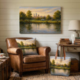 A scenic landscape art print of a lake and city skyline hangs on a white shiplap wall in a cozy, book-filled study. The print is displayed above a brown leather armchair with a matching landscape throw pillow, and a matching tote bag sits on the floor next to a wooden side table with a lamp.