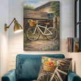A framed wall art print showing a vintage bicycle with a fruit basket hanging above a teal armchair in a styled room. The print depicts a rustic wooden cart, greenery, and flowers, while the chair includes a matching pillow with the bicycle design.